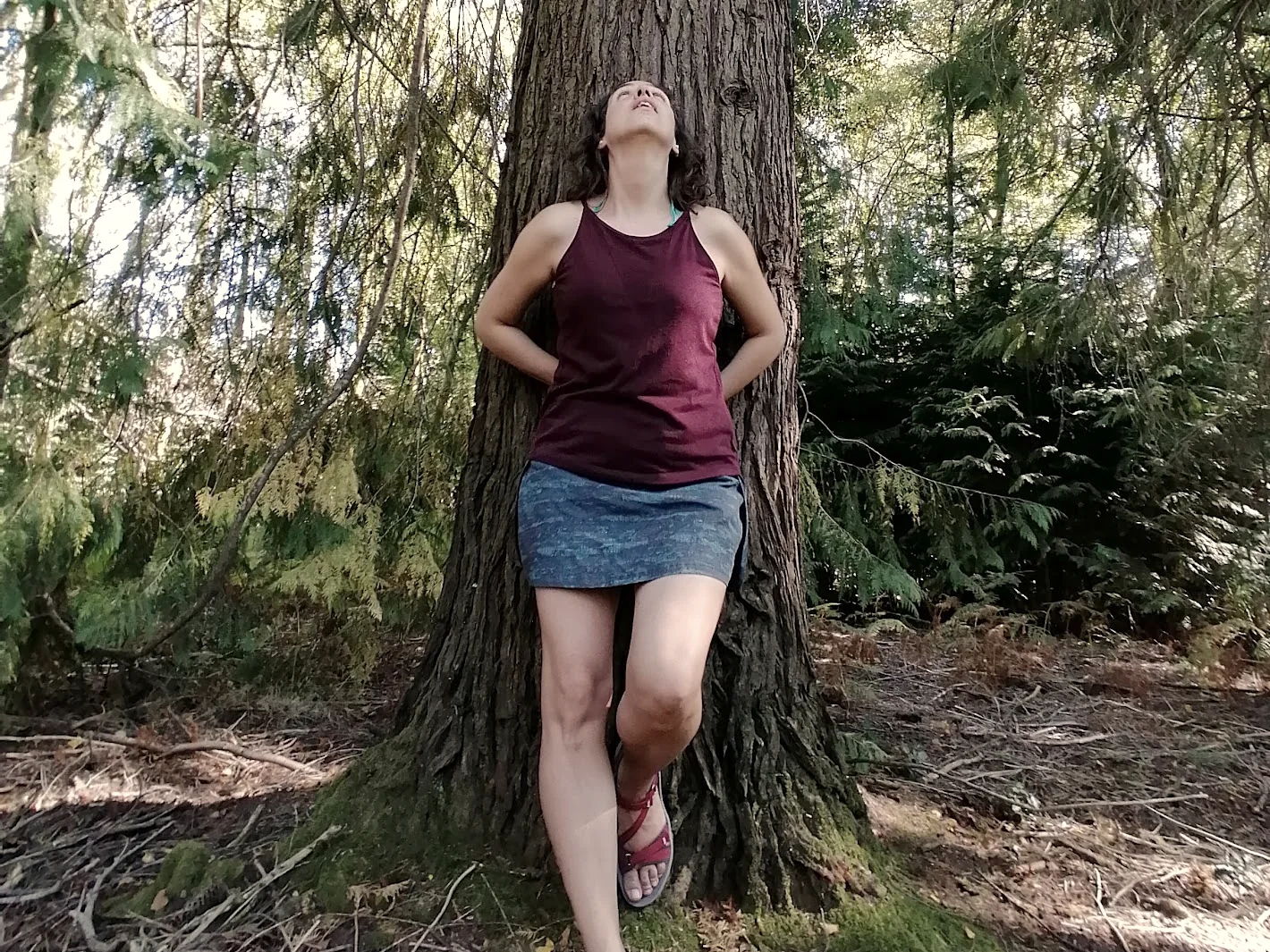 Eugénia Amaro, psicóloga, encostada ao tronco de um pinheiro, de cabeça levantada, num bosque.