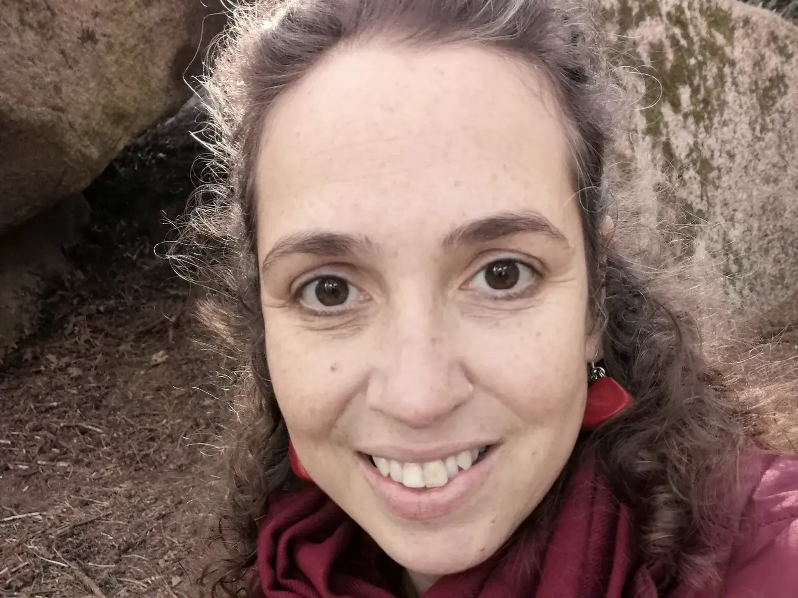 Eugénia Amaro, psicóloga, em retrato de luz natural, junto a uma rocha coberta de musgo.