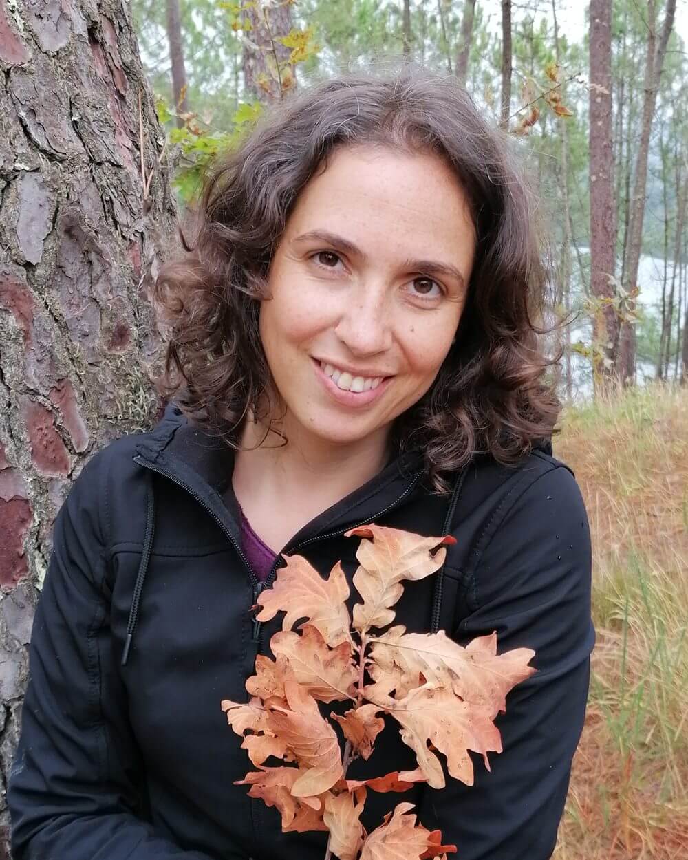 Eugénia Amaro, psicóloga clínica e psicoterapeuta, ao ar livre junto a um pinheiro